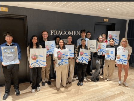The Fragomen team holding up the bicycle-and-flower-basket paintings they made at their event