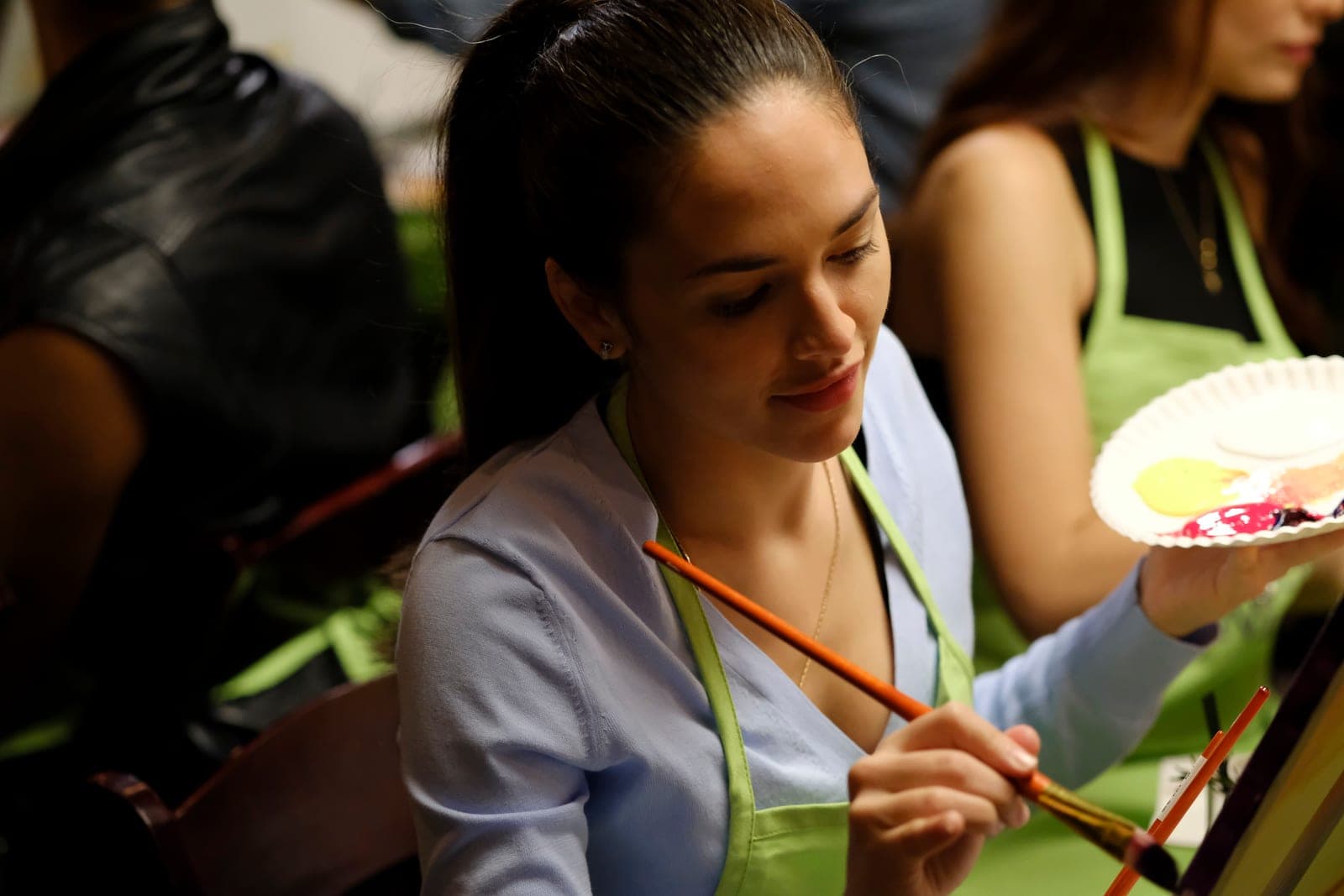 A guest concentrating on her canvas, palette in hand