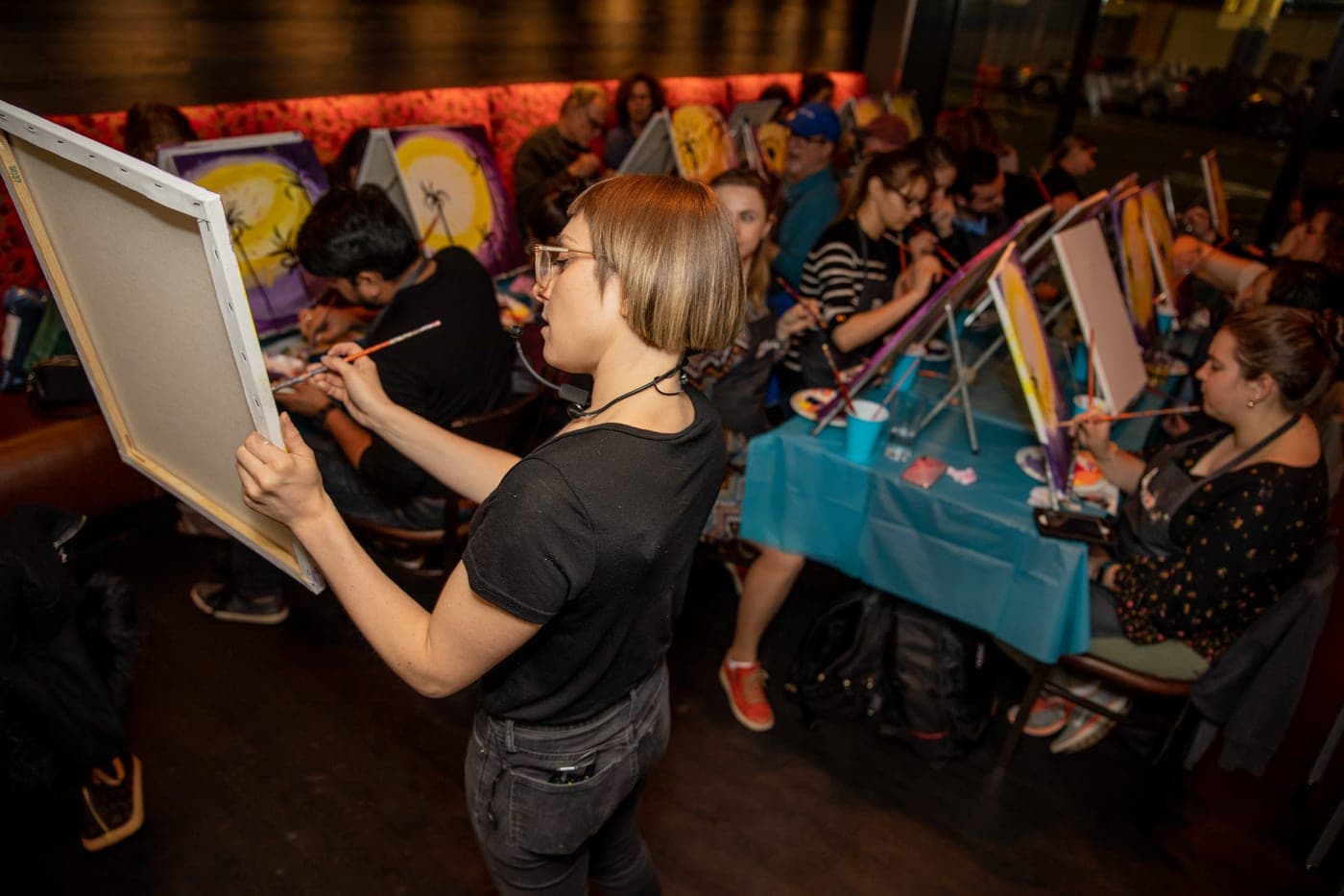 A Paint Nite host guiding guests through a painting