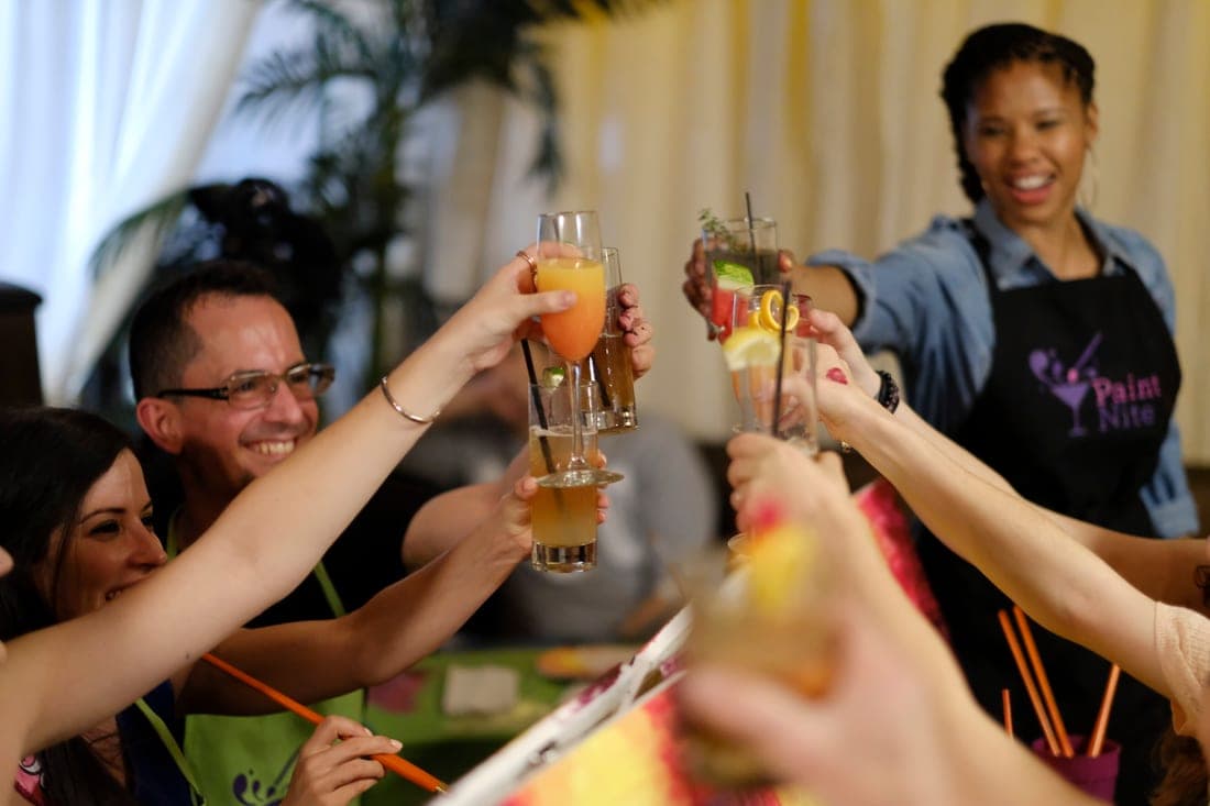 Guests toasting drinks at a Paint Nite event